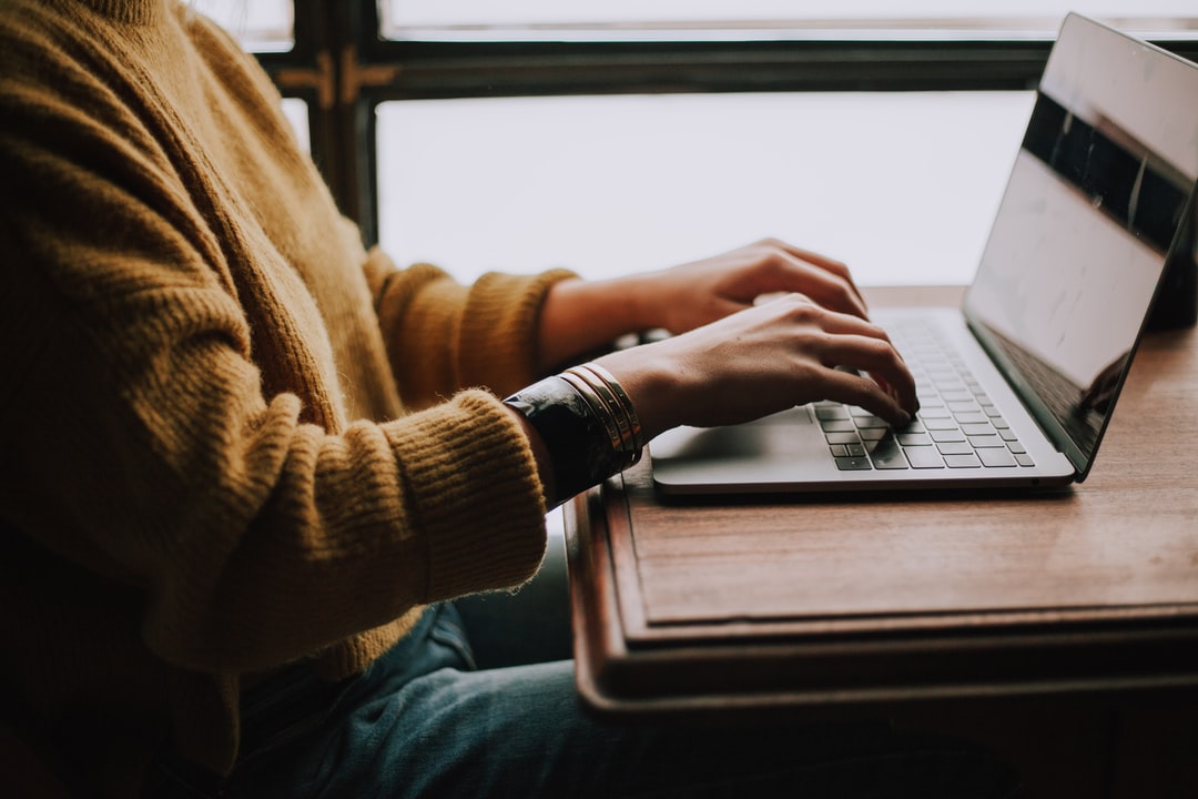 Femme noire qui écrit sur un clavier d'ordinateur portable.