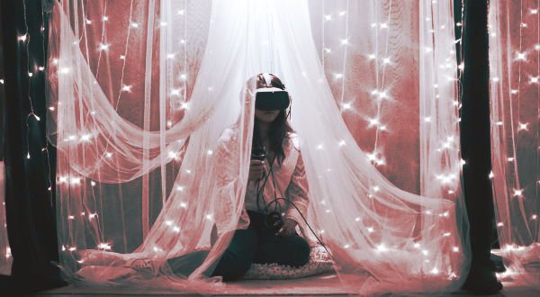 Fille avec un casque de réalité virtuelle sous un drap blanc